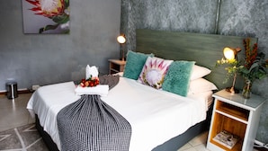 Une chambre à coucher moderne avec un grand lit, deux tables de chevet, une tête de lit et une œuvre d’art accrochée au mur.