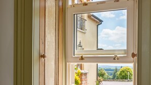 A bay window with a view of a garden and a building in the background. - Charming Old Farmhouse, Beautifully Restored - ideal base to explore SW Ireland (Coachford)