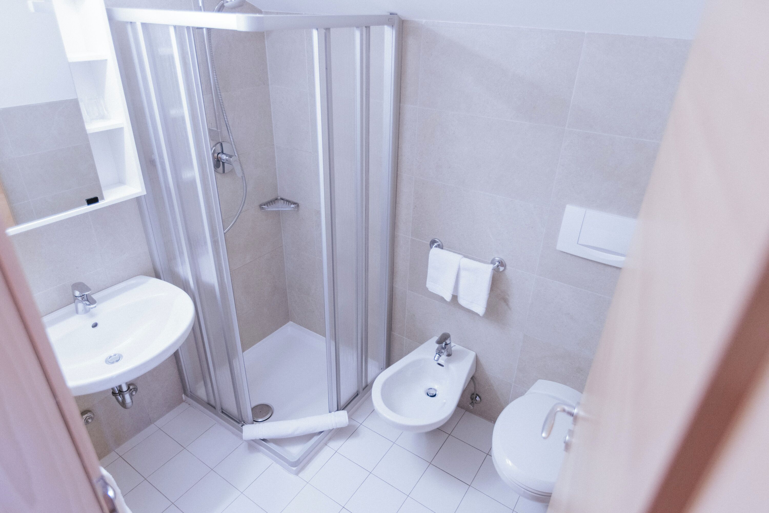 A modern bathroom with a glass-enclosed shower, a sink, a bidet, and a toilet.