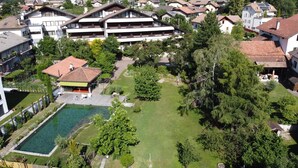 A residential area with a large building featuring multiple balconies, a swimming pool, and lush greenery. - Bio-Hotel & Residence Kaufmann (Ora)