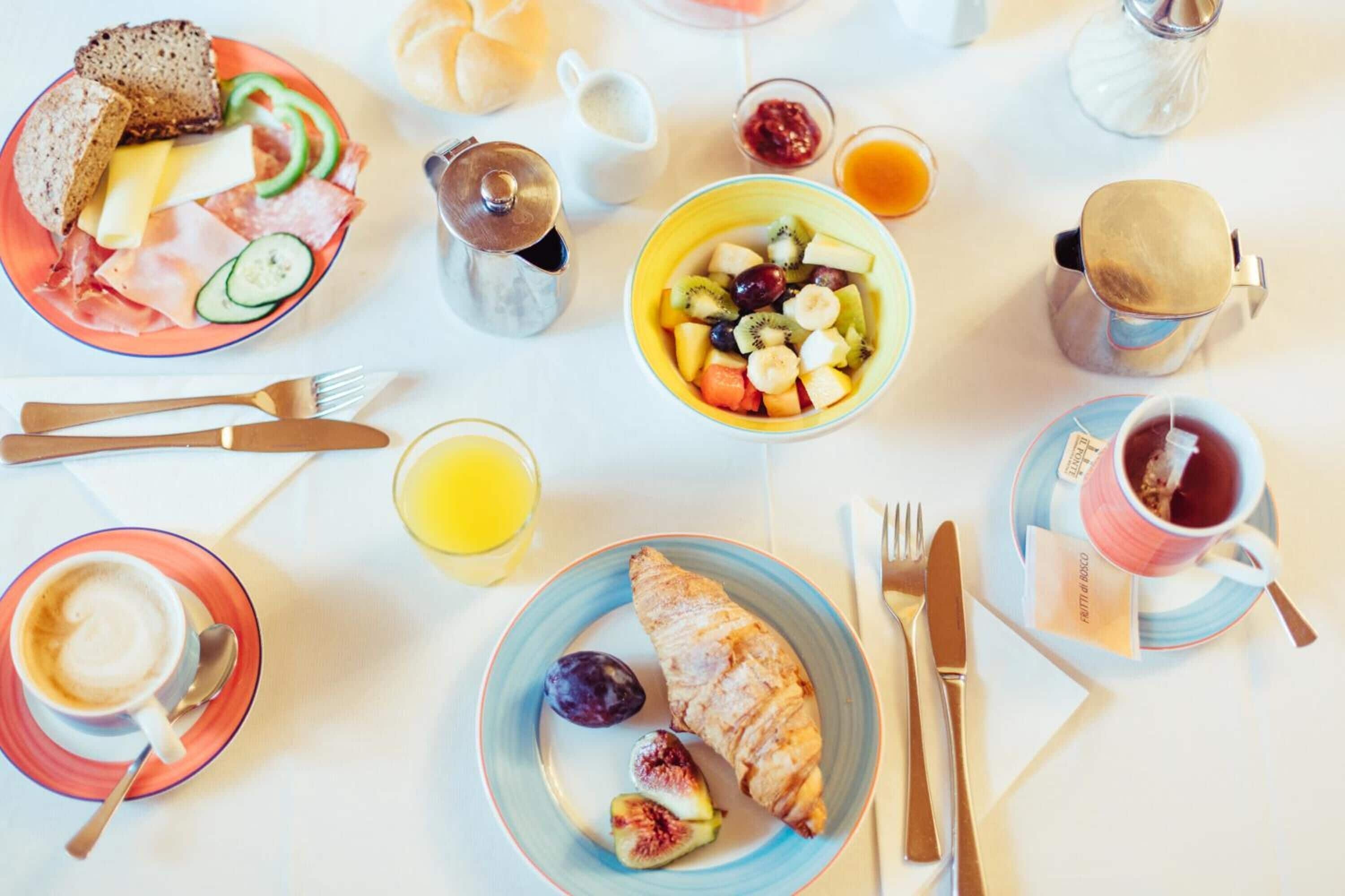 A breakfast setting with croissants, fruit, and coffee on a table.