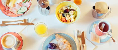 A breakfast setting with croissants, fruit, and coffee on a table.