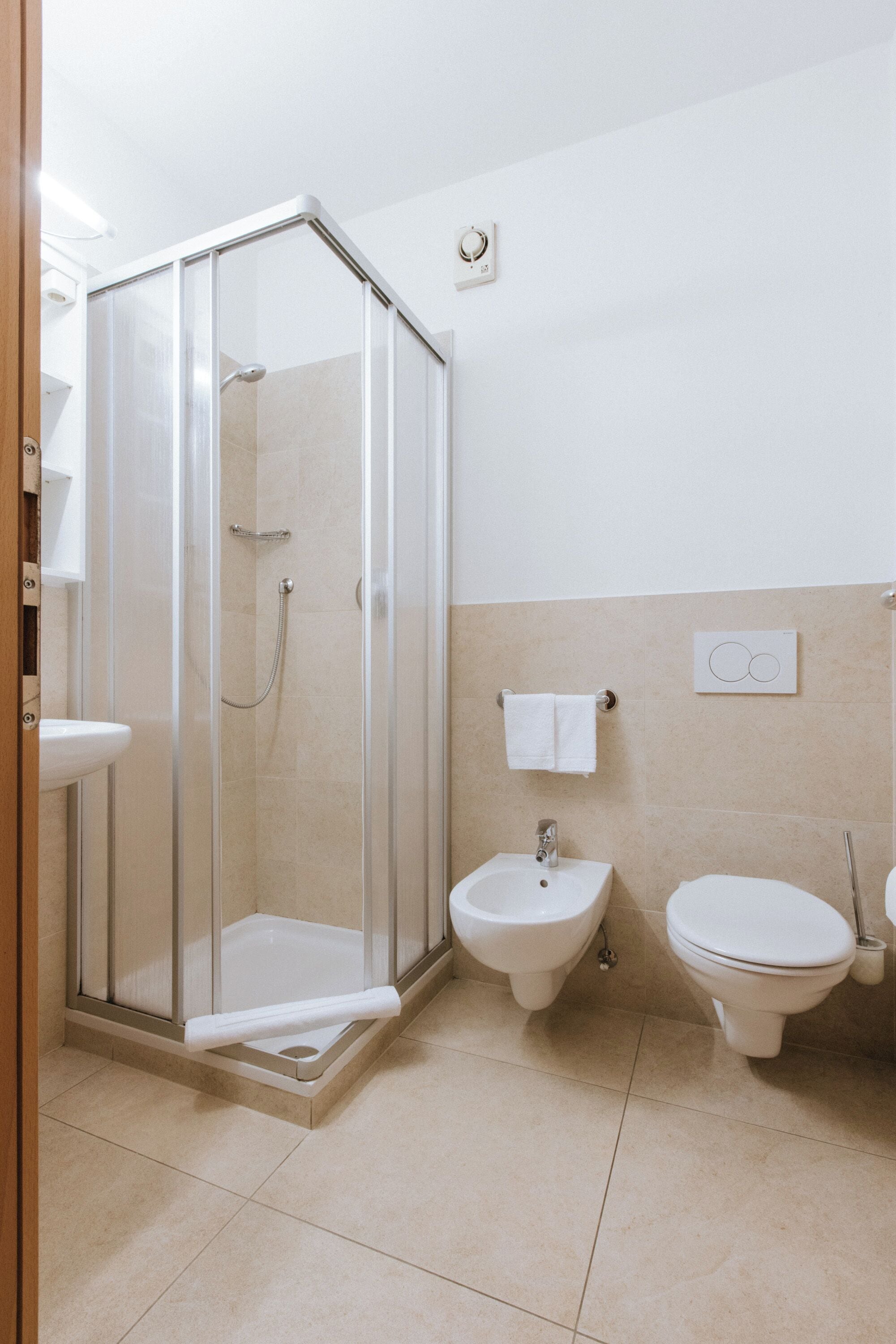 A bathroom with a glass-enclosed shower, a bidet, and a toilet.