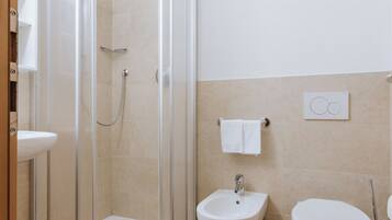 A bathroom with a glass-enclosed shower, a bidet, and a toilet.