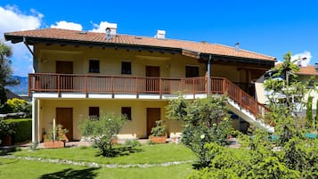 Ein zweistöckiges Gebäude mit Balkon, Treppe und Garten.