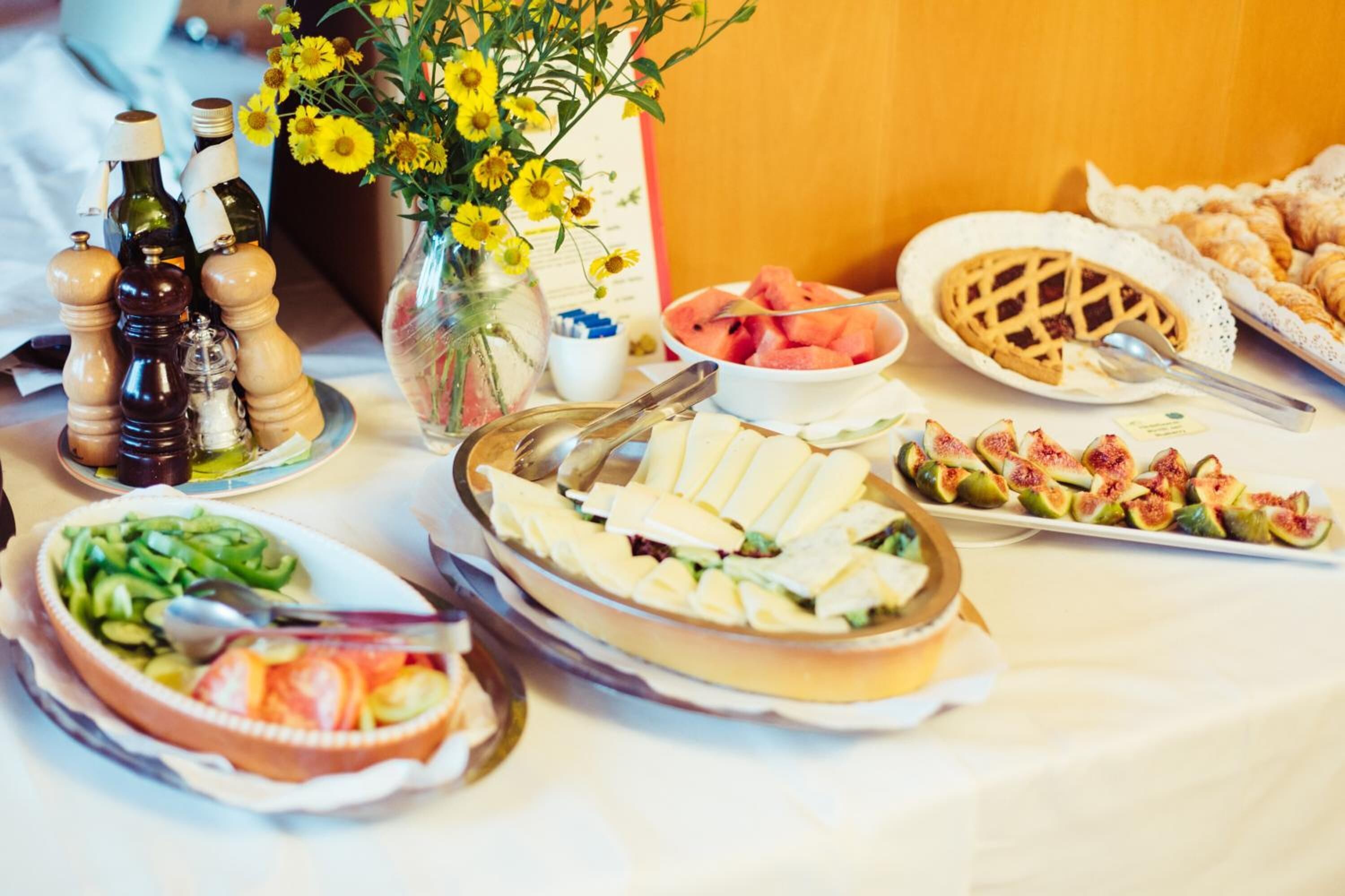 A table with various food items including a pie, watermelon, cheese, and figs.