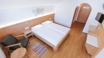 Een slaapkamer met een houten bed, een klein bureau, een stoel en een tv-meubel.