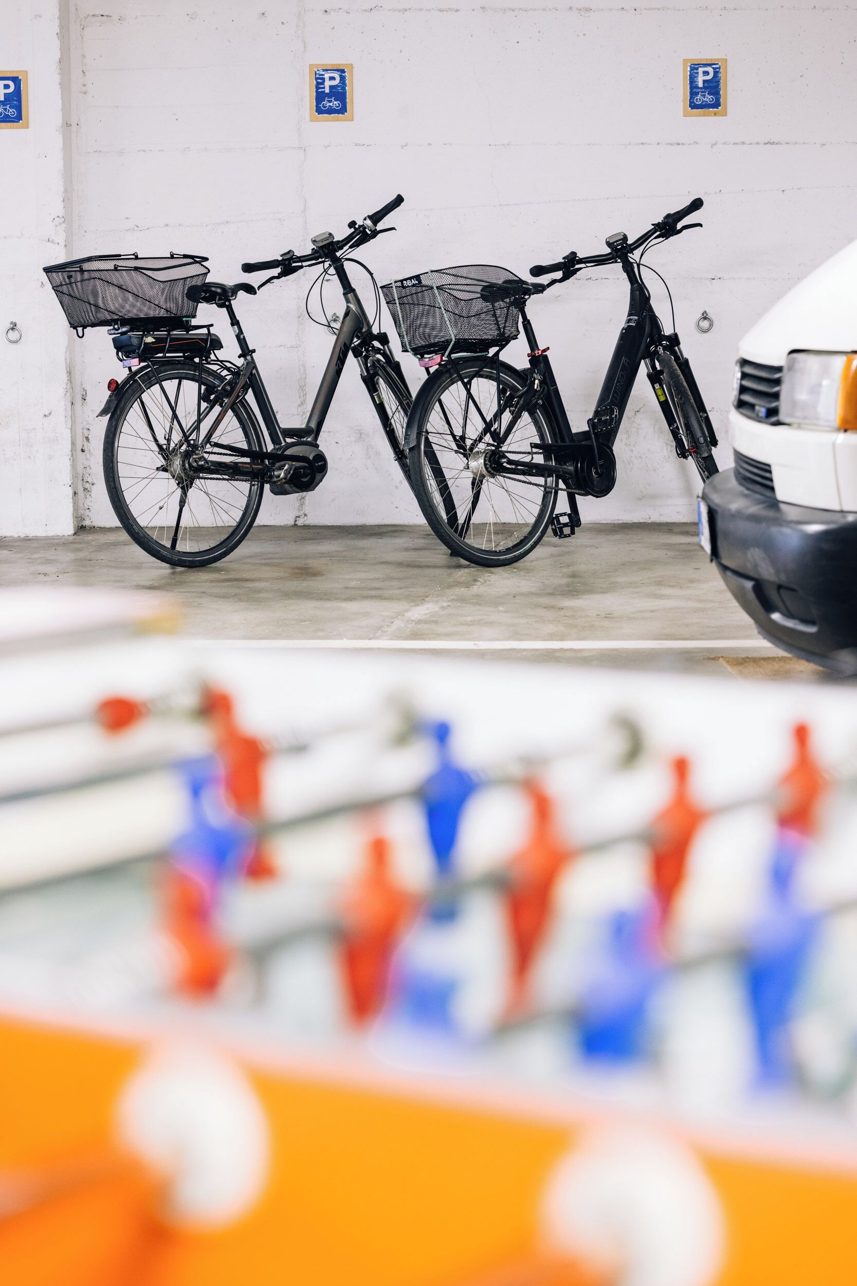 Un aparcamiento con bicicletas y un coche blanco.