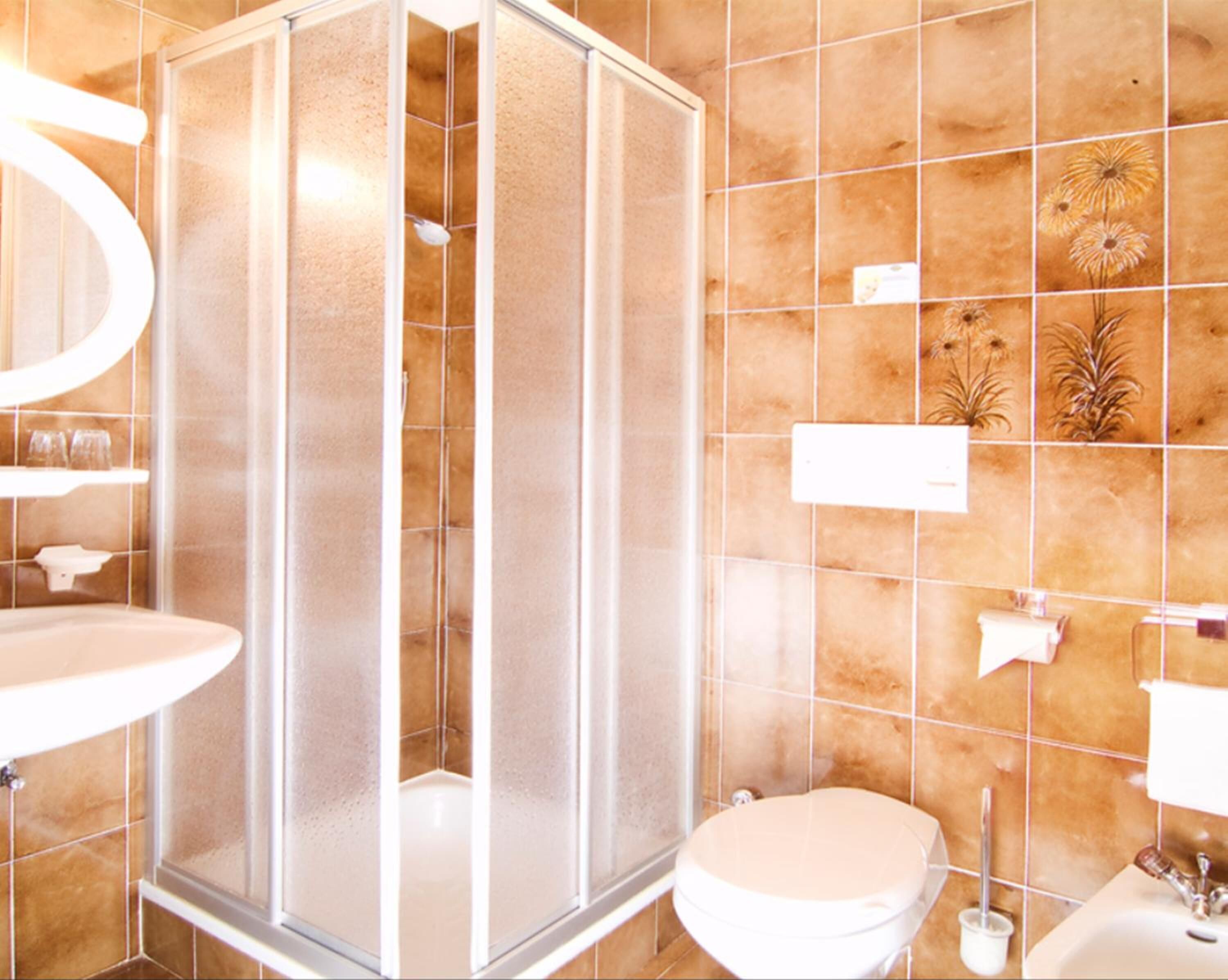Une salle de bain avec une douche à parois de verre, des toilettes et un lavabo.