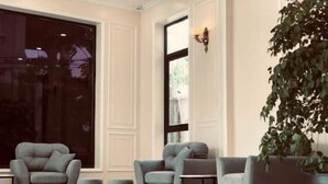 A modern living room with a large window, a potted plant, and a seating area with a small table. - Pure Stay (Hai Phong)