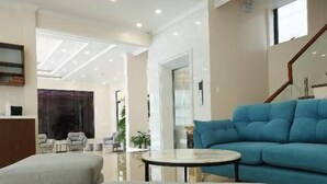 A modern living room with a blue sofa, grey ottomans, and a round coffee table. - Pure Stay (Hai Phong)