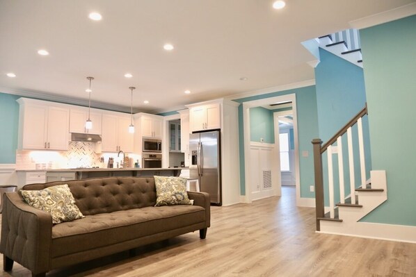 Relax in the living area with a tufted sofa and enjoy the kitchen's modern amenities.