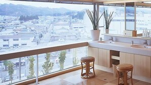Un baño moderno con un ventanal amplio, dos taburetes y un espejo.