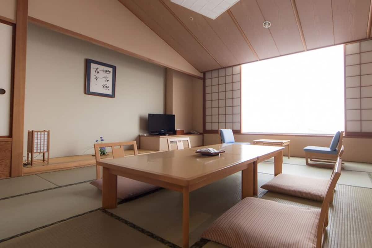 Perinteinen japanilainen huone, jossa on tatamimatto, matala pöytä, televisio ja liukuovi.