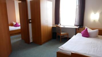 Una habitación de hotel con una cama, un escritorio, una silla y un armario.