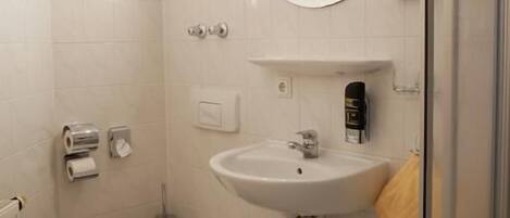 Un baño moderno con inodoro, lavabo y cabina de ducha de vidrio.