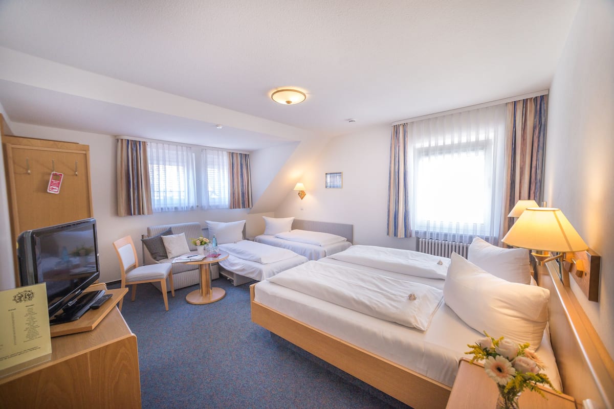 Habitación de hotel con dos camas, televisor, escritorio y lámpara.