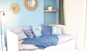 A modern living room with a white sofa, blue cushions, a wooden coffee table, and decorative mirrors on the blue wall. - House for 4 travelers, with private courtyard - between the city center and the port (Saint-Brieuc)