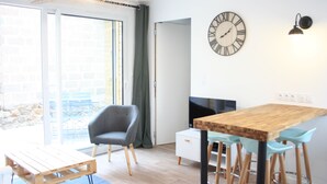 A modern kitchen with a wooden table, bar stools, a grey chair, and a wall clock. - House for 4 travelers, with private courtyard - between the city center and the port (Saint-Brieuc)