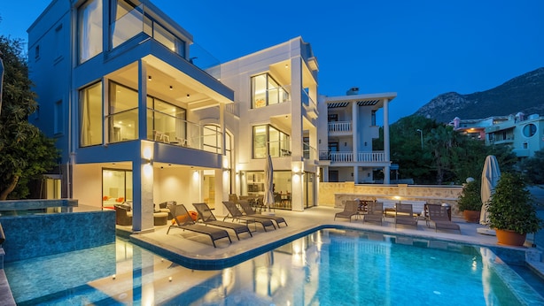 Un bâtiment moderne à deux étages, doté d’une piscine, d’un espace extérieur aménagé et offrant une vue sur les montagnes.