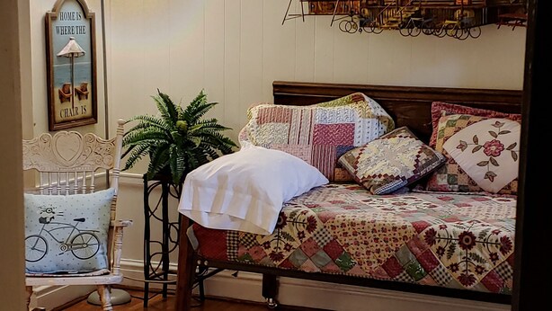 Un dormitorio con una cama de madera, una mesita de noche, una lámpara, una silla y un elemento decorativo en la pared.