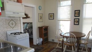 Una cocina con estufa, lavaplatos y comedor con sillas y mesa.