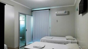 A hotel room with two beds, a shower, and an air conditioning unit. - Hotel Minas (Tres Marias)
