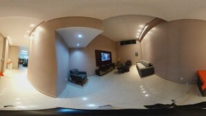 A modern living room with a flat-screen TV, a sofa, a coffee table, and a small table with a lamp. - Hotel Minas (Tres Marias)