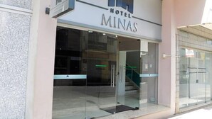 A hotel entrance with a glass facade, a staircase leading inside, and a sign reading "HOTEL MINAS". - Hotel Minas (Tres Marias)