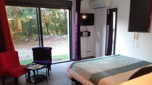 Un dormitorio con una cama, una silla, una mesita y un televisor.