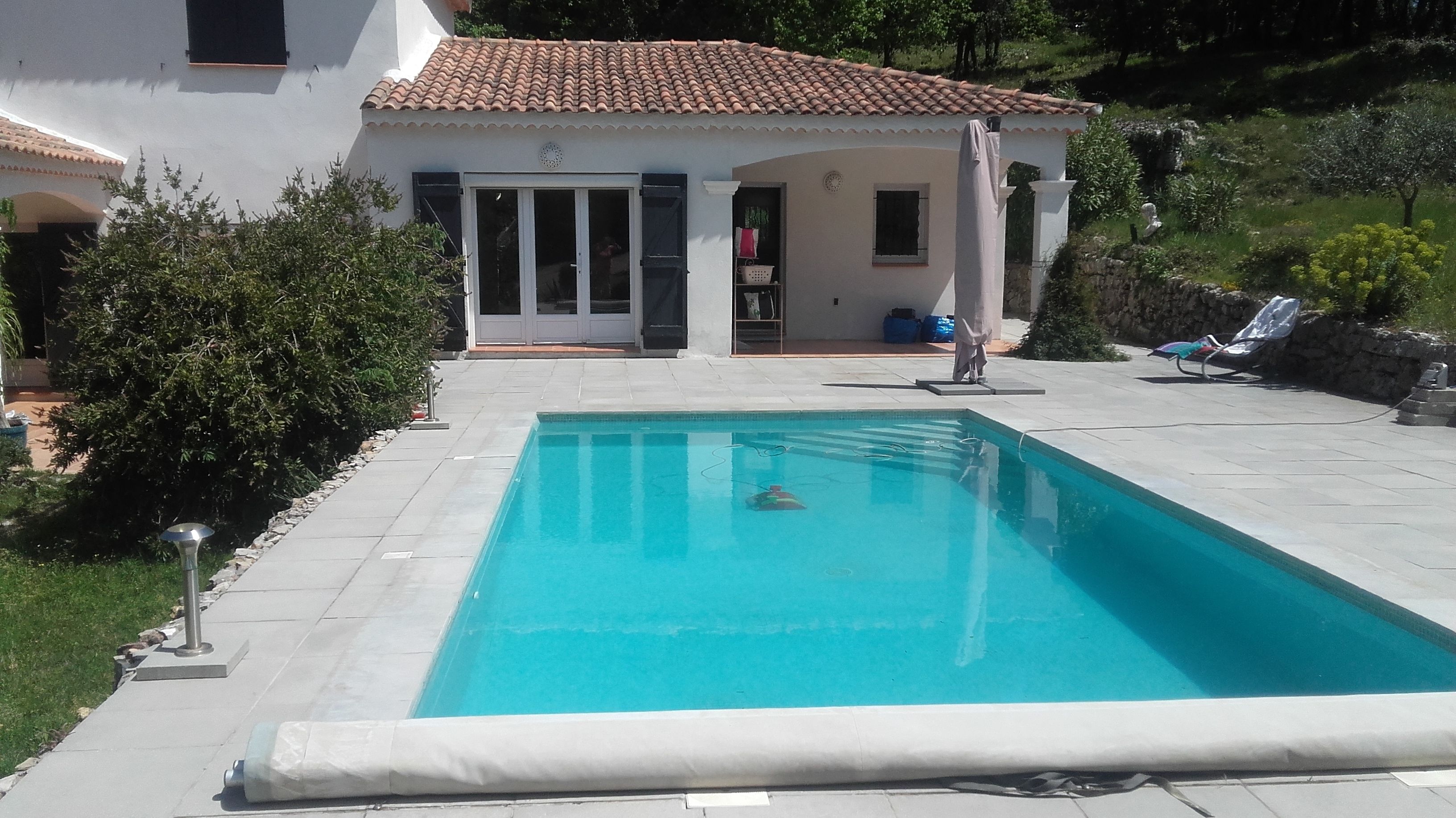 Una piscina rectangular con un borde empedrado a su alrededor.