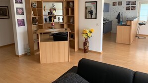 Un espacio habitable moderno con una zona de comedor de madera, una cocina y un sofá negro.