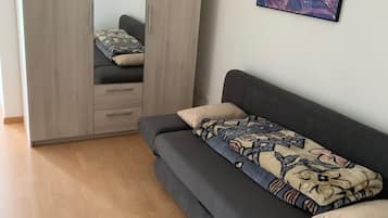 Un dormitorio moderno con un sofá gris, un armario grande y un cuadro abstracto y colorido en la pared.