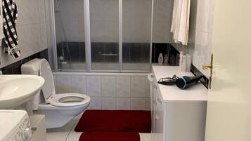 Un baño con inodoro, lavabo y zona de ducha.