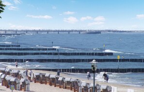 A beach with rows of numbered beach chairs and umbrellas, a pier in the background, and a clear sky. - 1 bedroom gorgeous apartment in Kolobrzeg (Kolobrzeg)