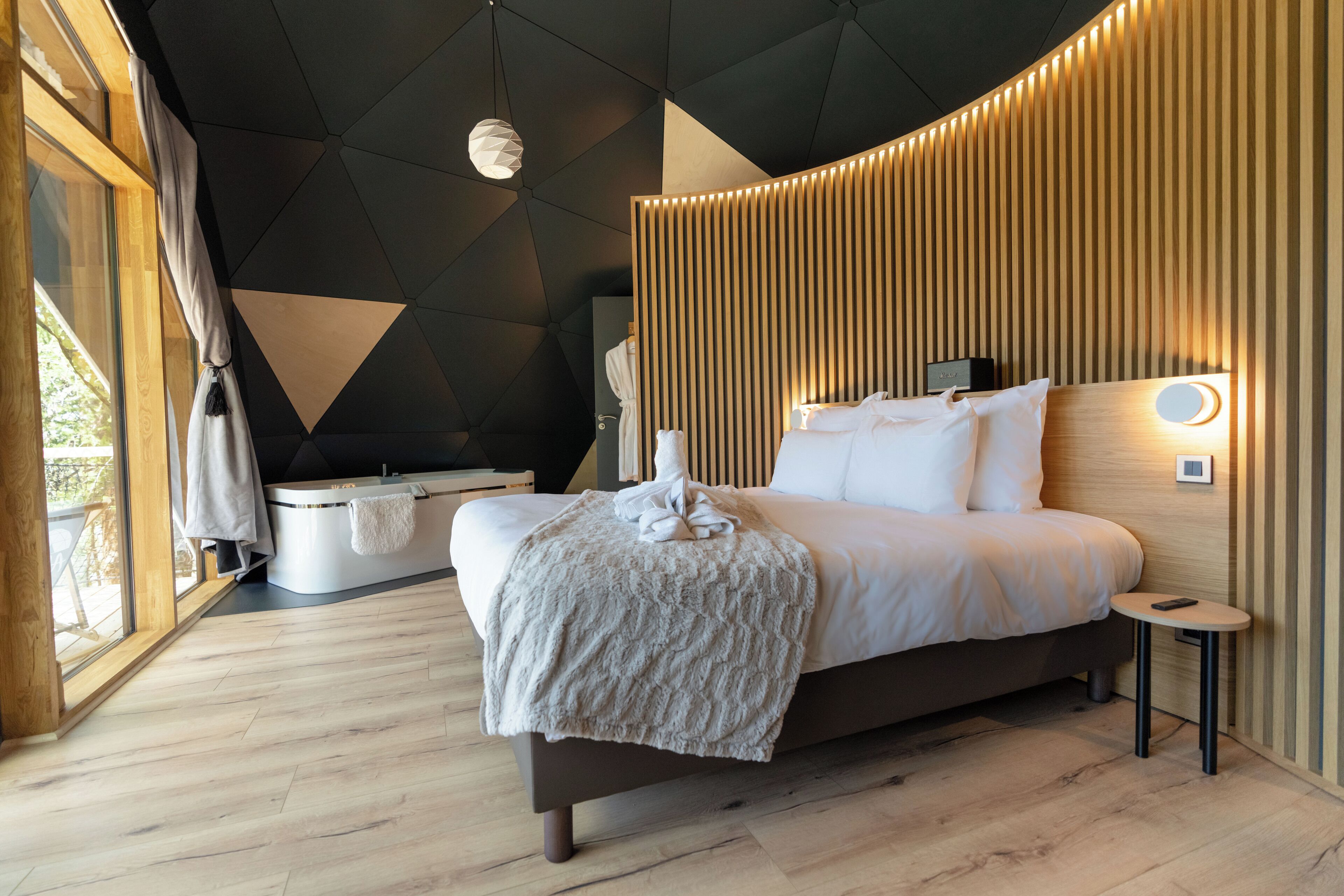 Ein modernes Schlafzimmer mit einem großen Bett, einer integrierten Badewanne und Blick ins Freie.