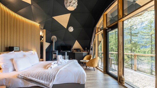 Habitación de hotel moderna con una cama grande, un escritorio y vistas al exterior.