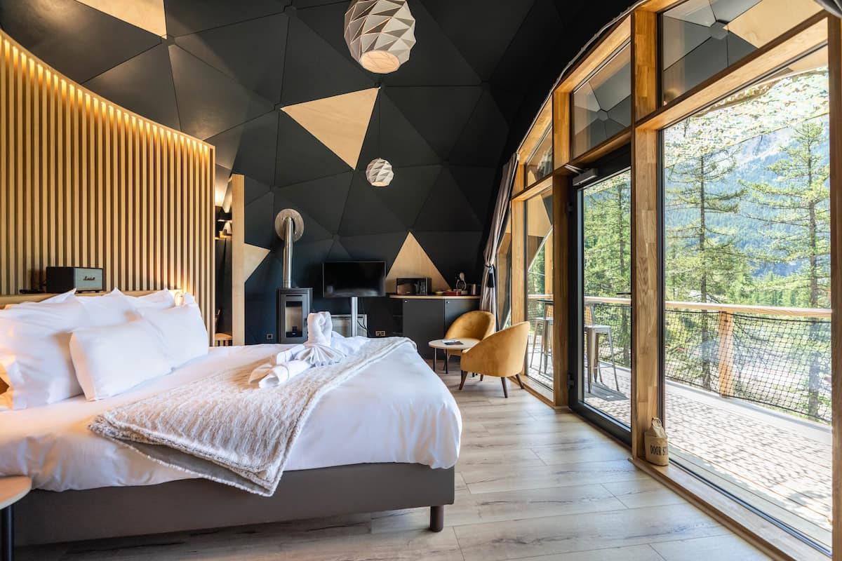 Quarto de hotel moderno com uma cama grande, uma mesa de trabalho e vista para o exterior.