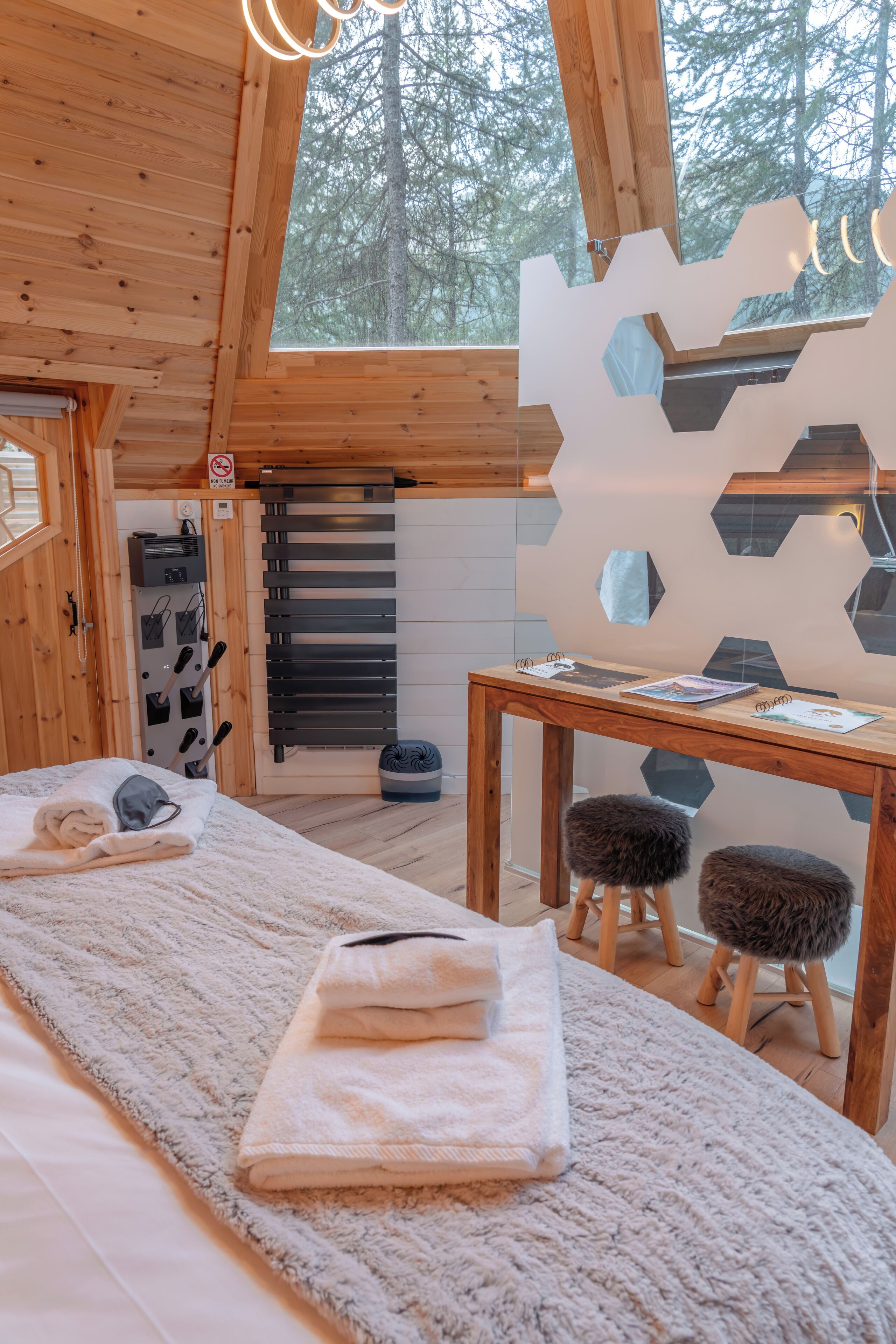 Une chambre confortable dans un chalet, avec un lit, une table avec des serviettes, une chaise et une vue sur les arbres par la fenêtre.