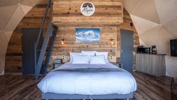 Quarto com cama, parede de madeira com um logotipo, escada e vista de uma montanha.