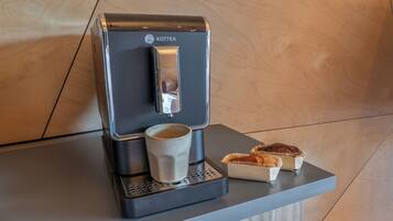 A coffee machine with a cup and two pastries on a countertop.