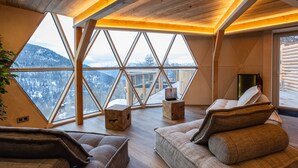 Una habitación acogedora con un ventanal grande, vigas de madera y vistas a montañas nevadas.