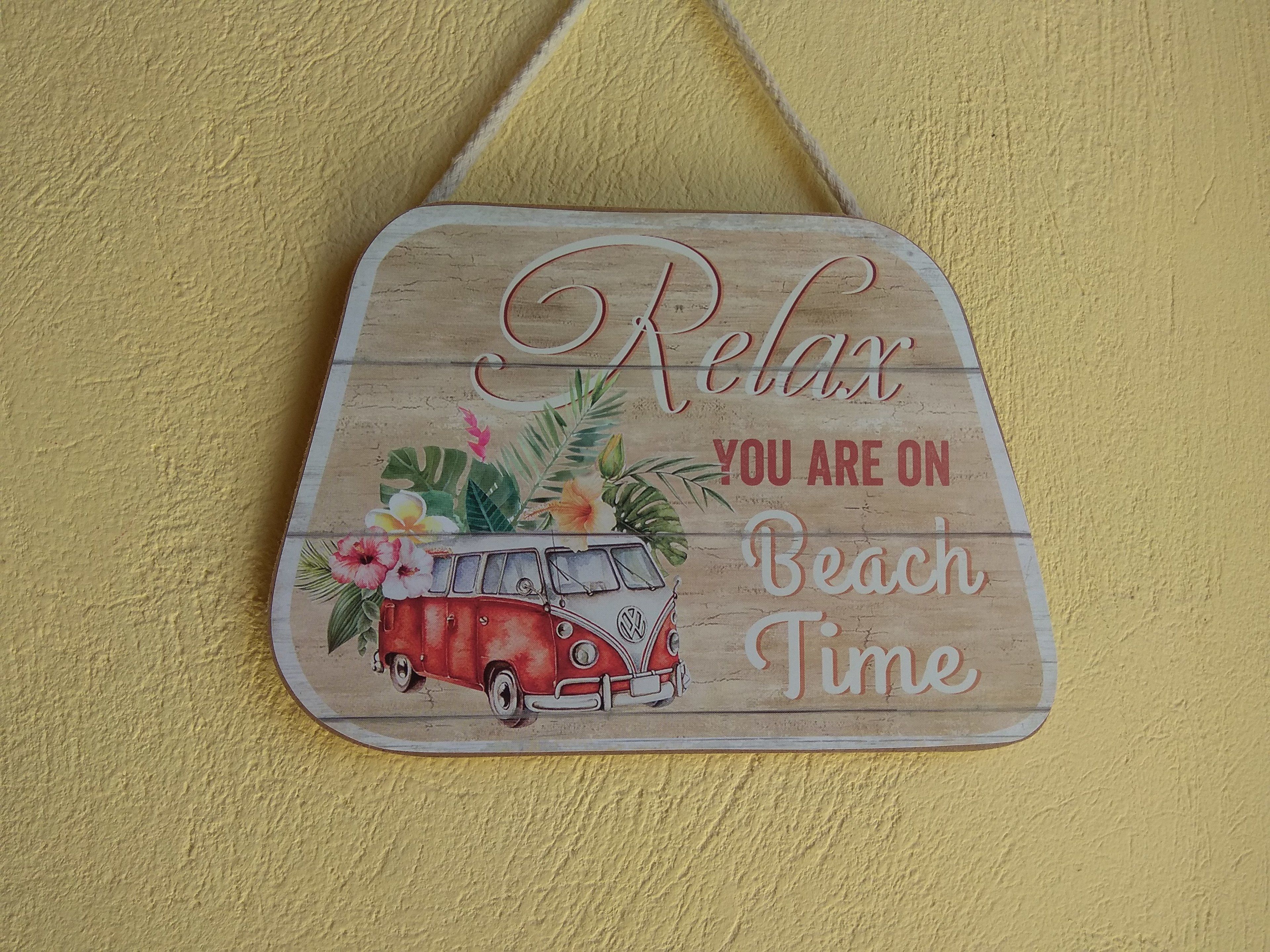 Un cartell de fusta amb una furgoneta antiga i flors tropicals, amb la frase "Relax, has arribat a Beach Time".