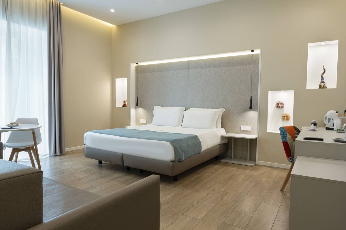A modern hotel room with a large bed, bedside tables, a desk, and a chair.