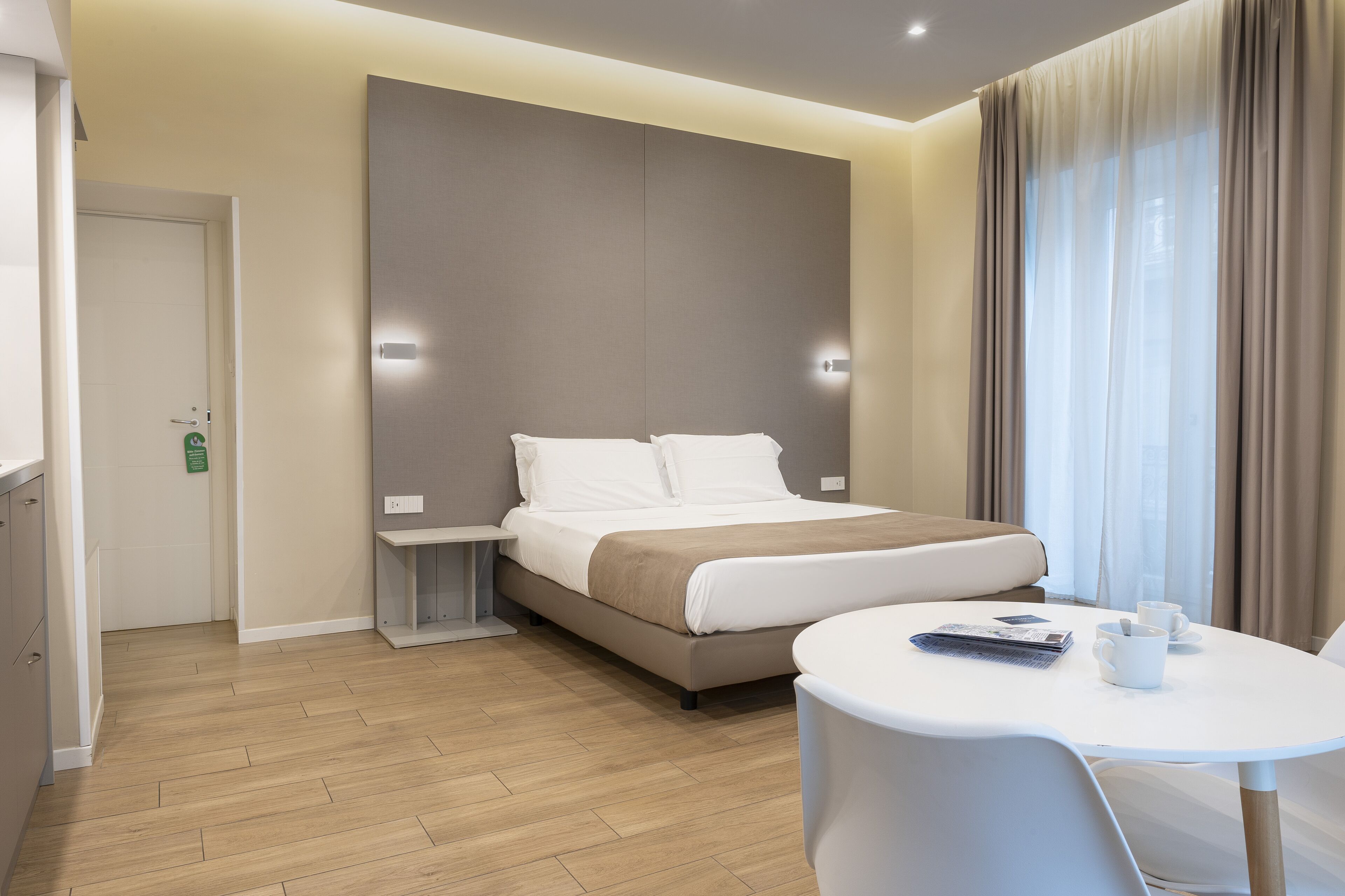 Une chambre d’hôtel moderne équipée d’un lit, d’une table de chevet et d’une petite table sur laquelle se trouvent des tasses et une télécommande.