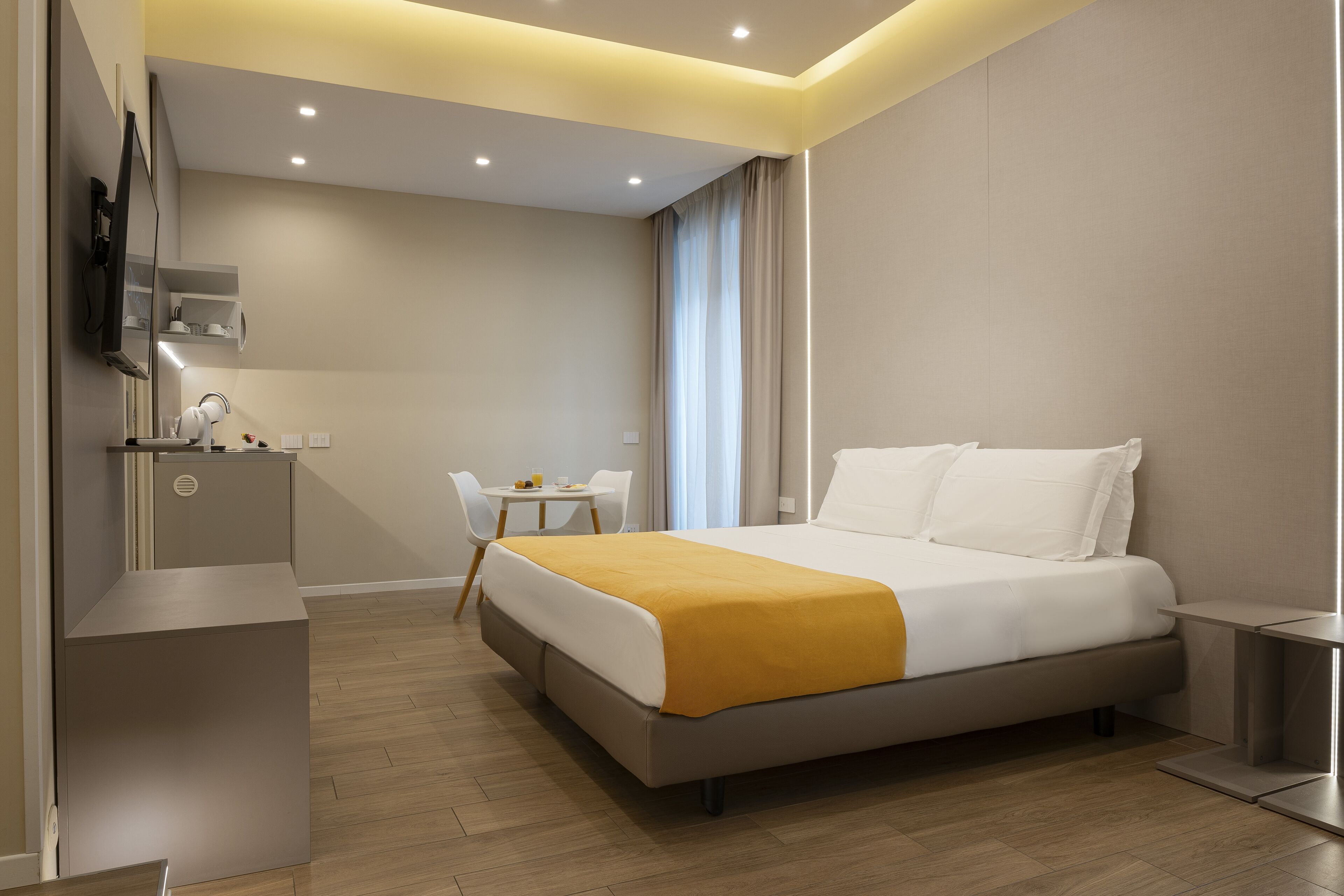 A modern hotel room with a large bed, a desk, and a chair.