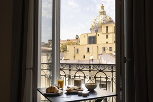 Un balcone con un tavolo apparecchiato per la colazione, vista su un edificio con una cupola caratteristica e cielo sereno.
