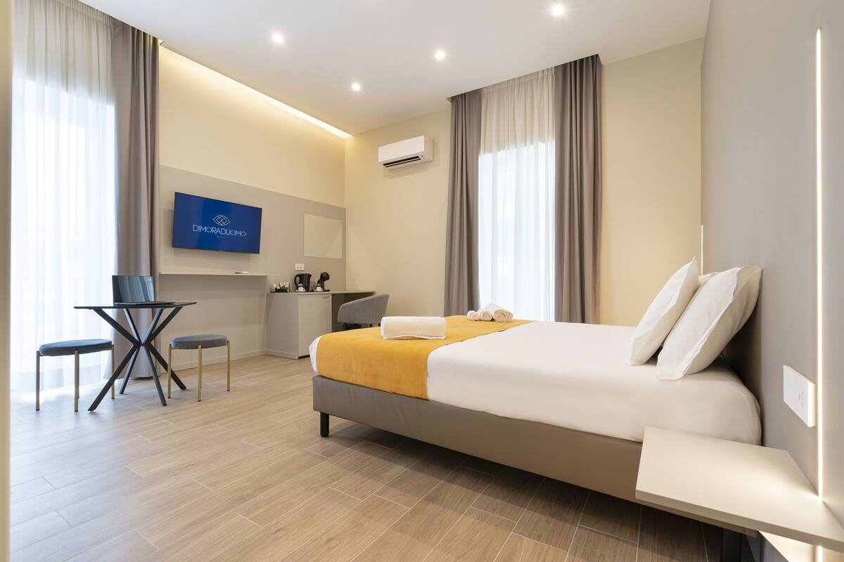 A modern hotel room with a bed, a desk, and a television.
