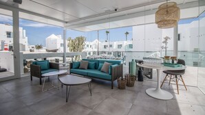 A modern living room with a teal sofa, a round coffee table, and a hanging light fixture. - Guinate Club Apartamentos (Tías)