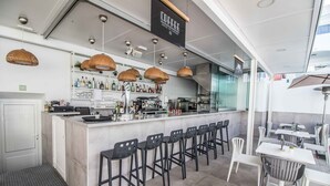 A modern coffee shop with a bar area, seating, and a variety of beverages and snacks. - Guinate Club Apartamentos (Tías)
